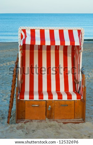 a striped german beach chair. Strandkorb. on the beach on a sunny day. used on cold and hot days