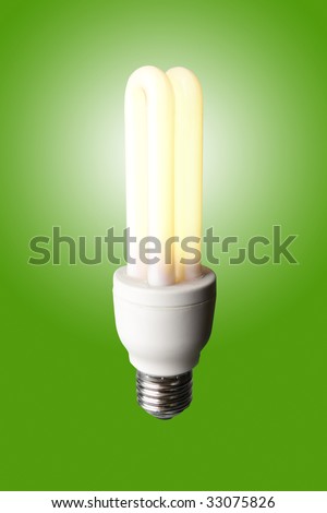 Energy saver light bulb shining on green background with clipping path