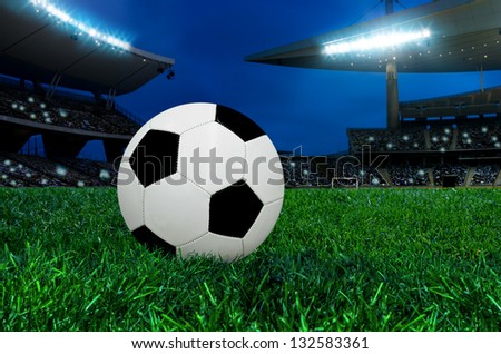 Soccer ball on green grass in an crowded big stadium