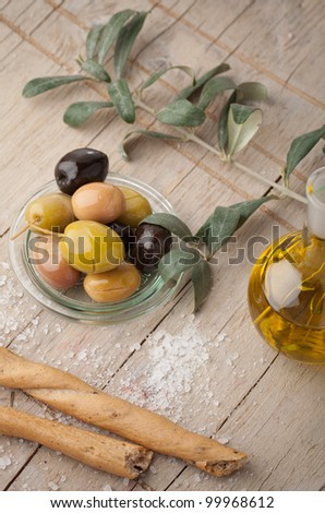 Olive oil bottle, olives and pretzels on wooden table