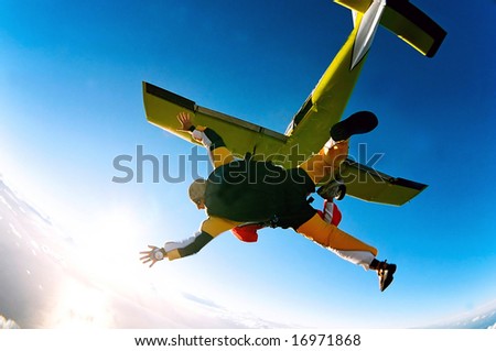 Tandem skydiver in action parachuting, seen in mid air position.