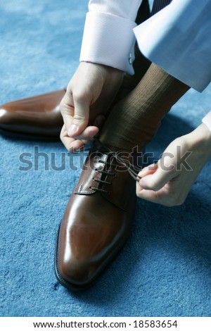 Man putting on brown leather shoes for work