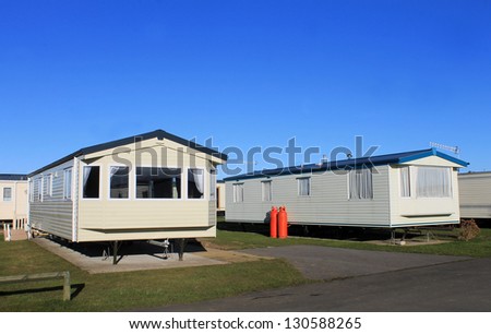 Caravans parked in modern trailer park with blue sky background.