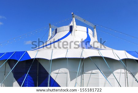 Blue and white big top circus tent with sky background.