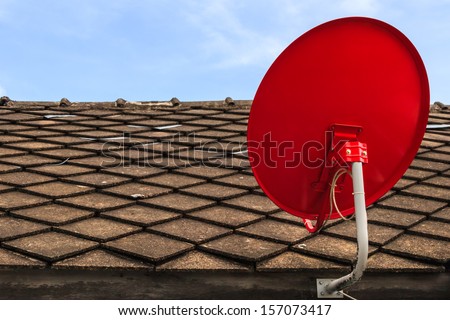 Red Satellite TV Receiver Dish on the Old Tiles Roof