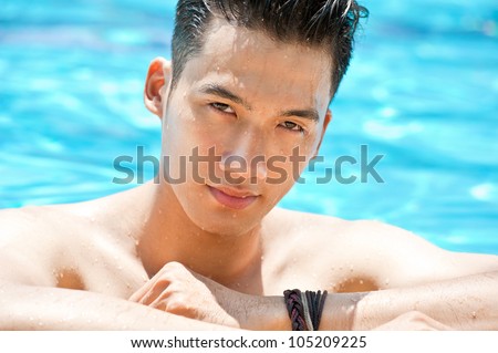 Wet Asian man looking at camera in swimming pool