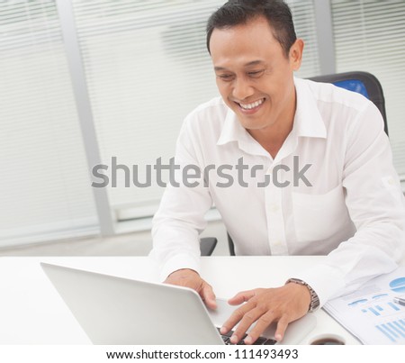 Happy manager typing on laptop at his table