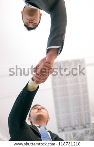 Vertical shot of young business people shaking hands to conclude the deal
