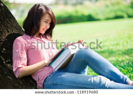 Lovely girl studying outside in the park on a sunny summer day