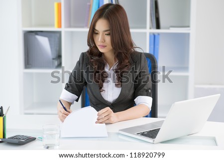 Pretty manager signing documents in her office