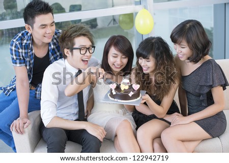 Cheerful birthday girl cutting a chocolate cake to share with her friends