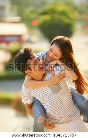 Young Asian man giving his girlfriend piggy back ride Shutterstock - PuzzlePix