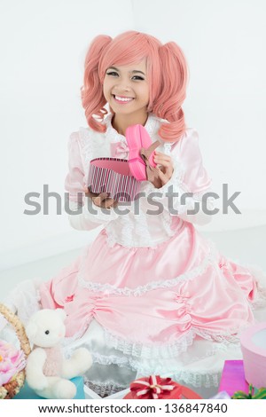 Vertical portrait of a cute princess in pink opening a gift-box