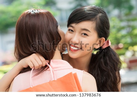 Lovely friends hugging being glad about their successful shopping