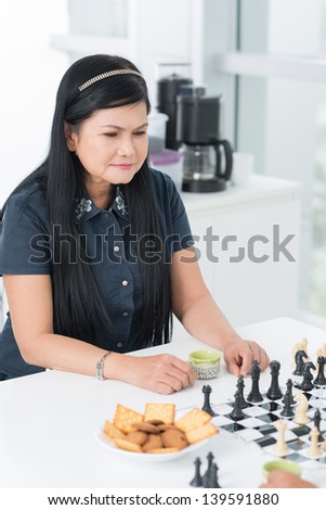 Vertical image of a senior woman being in deep thoughts in the kitchen