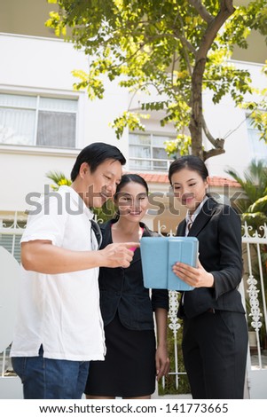 Vertical Image of a realtor with her clients choosing different variants in the Internet