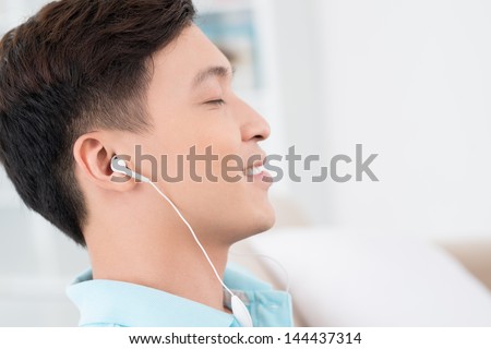 Close-up image of a guy in a profile listening to music via earphones