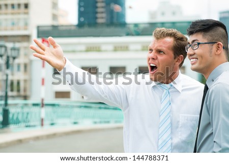Businessman with a what-the-heck look on his face observing the downtown together with his colleague