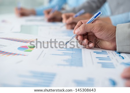Close-up of human hands analyzing the business diagrams on the foreground