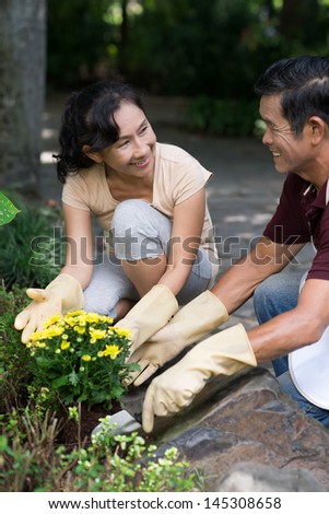 Vertical image of matures planting flowers in the garden