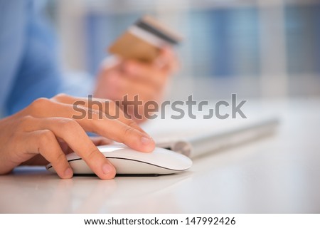 Close-shot of a human hand clicking a computer mouse on the workplace