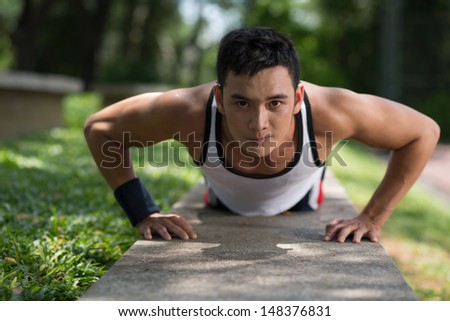 Close-up image of a young sportsman doing push-ups outside