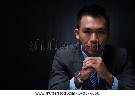 Copy-spaced portrait of a young businessman thinking over the business strategy over a black background