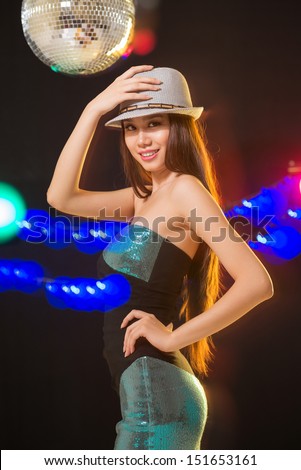Vertical portrait of a cheerful lady smiling and looking at camera in the nightclub