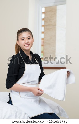 Vertical portrait of a young housekeeper cleaning the apartment inside