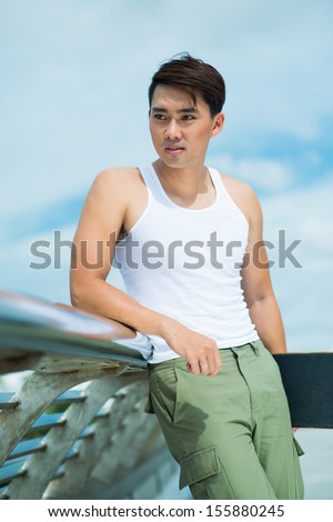 Vertical image of a cool guy with a skate board over sky