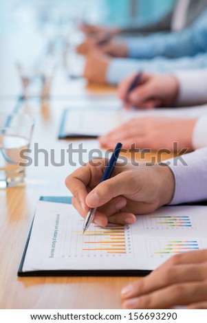 Close-up of human hands working with a business graphics on the foreground