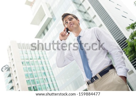 Angle view of a young busy businessman on the phone standing outside
