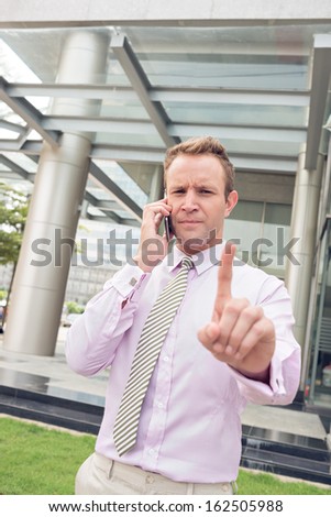 Vertical portrait of a serious businessman concentrated at the telephone call and gesturing standing outside