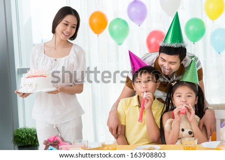 Image of a father having fun with his children while a mother holding birthday cake on the foreground