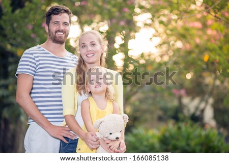 Copy-spaced portrait of a young friendly family standing and posing at camera in the park