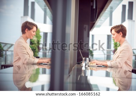 Image of a businesswoman working while having her business lunch at the modern restaurant