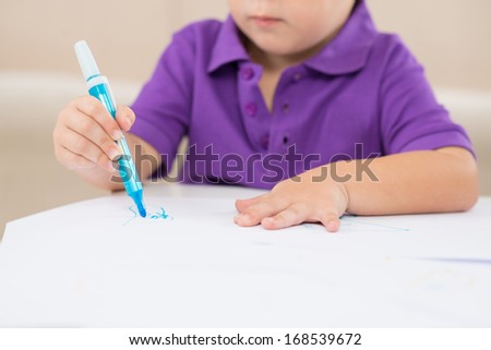 Cropped image of a little boy drawing his first picture on the foreground