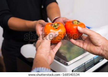 Cropped image of a buyer giving to the seller the vegetables on the foreground
