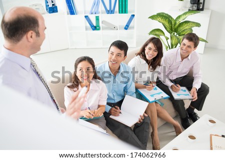 Image of a CEO of the company explaining the strategy to his working team at the meeting on the foreground