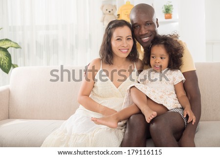 Copy-spaced portrait of a mixed family smiling and looking at camera