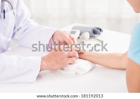 Cropped image of a doctor measuring patient\'s pulse on the foreground