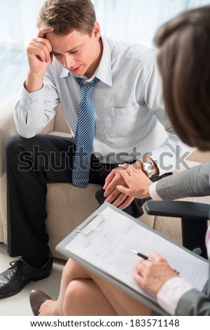 Vertical image of a psychiatrist comforting worried patient at session