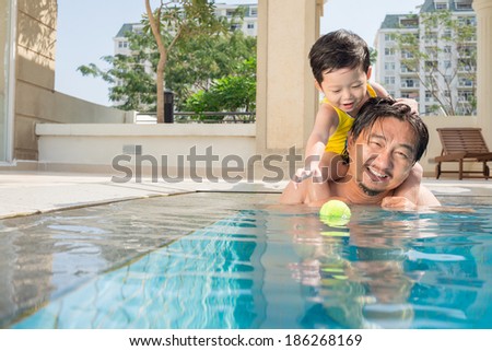 Man playing with his little son in swimming pool