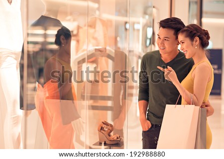 Young woman showing something in the shop window to her husband