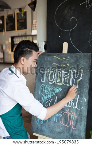 Waiter writing todayÃ?Â¢??s special on the board in the cafe
