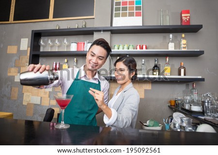 Cafe owner teaching waiter how to make a drink