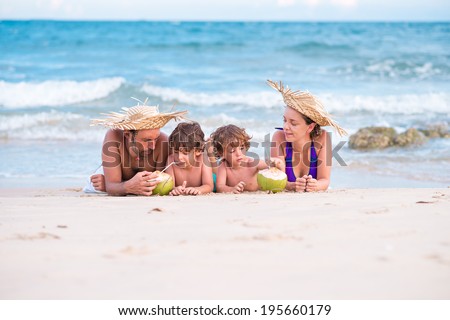 Family lying on the beach and drinking coconut milk