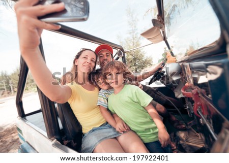 Woman taking photo of herself and her family with the smartphone while sitting in the off-road vehicle