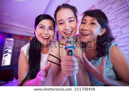 Three Vietnamese women singing a song in the karaoke bar