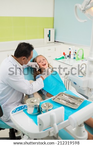 Experienced doctor examining teeth of a young girl
